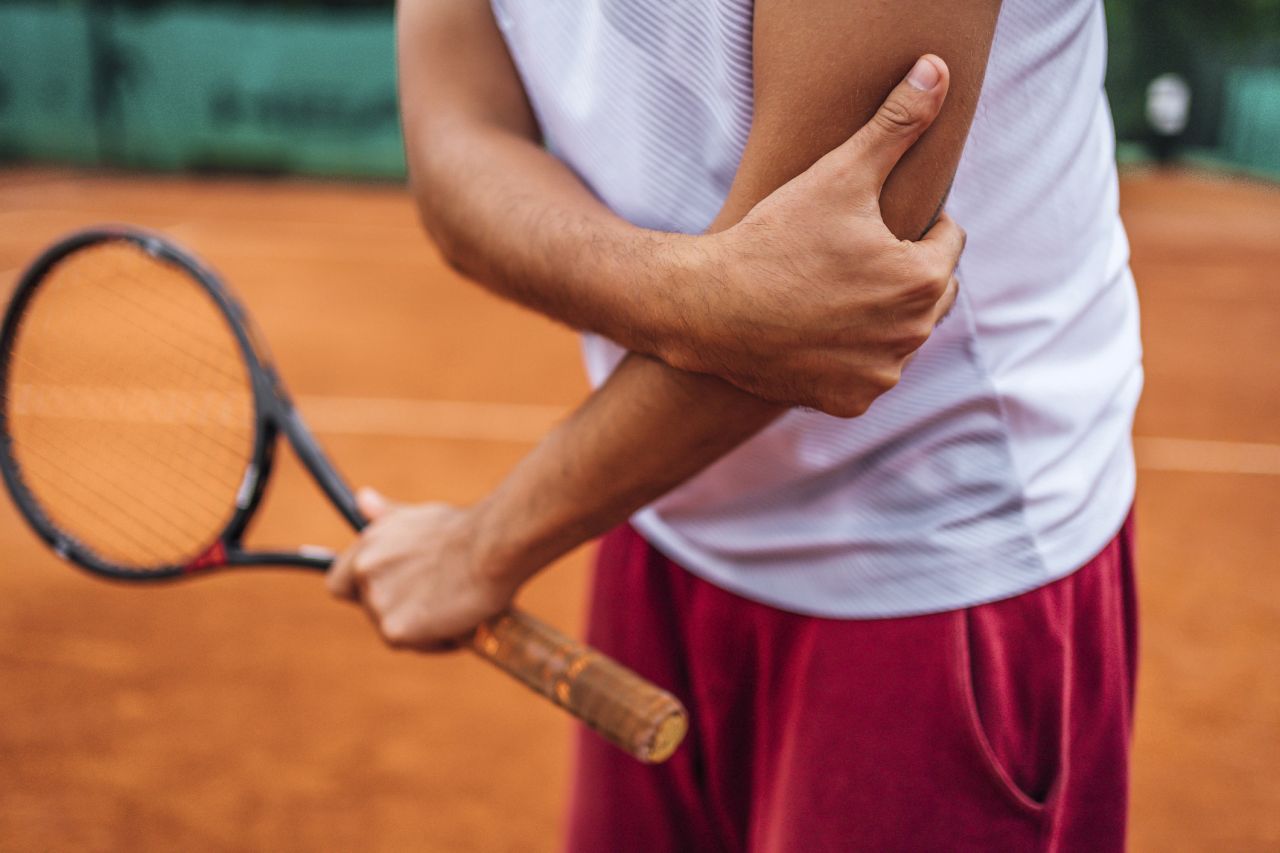 Tennisspieler hält sich am Ellenbogen 