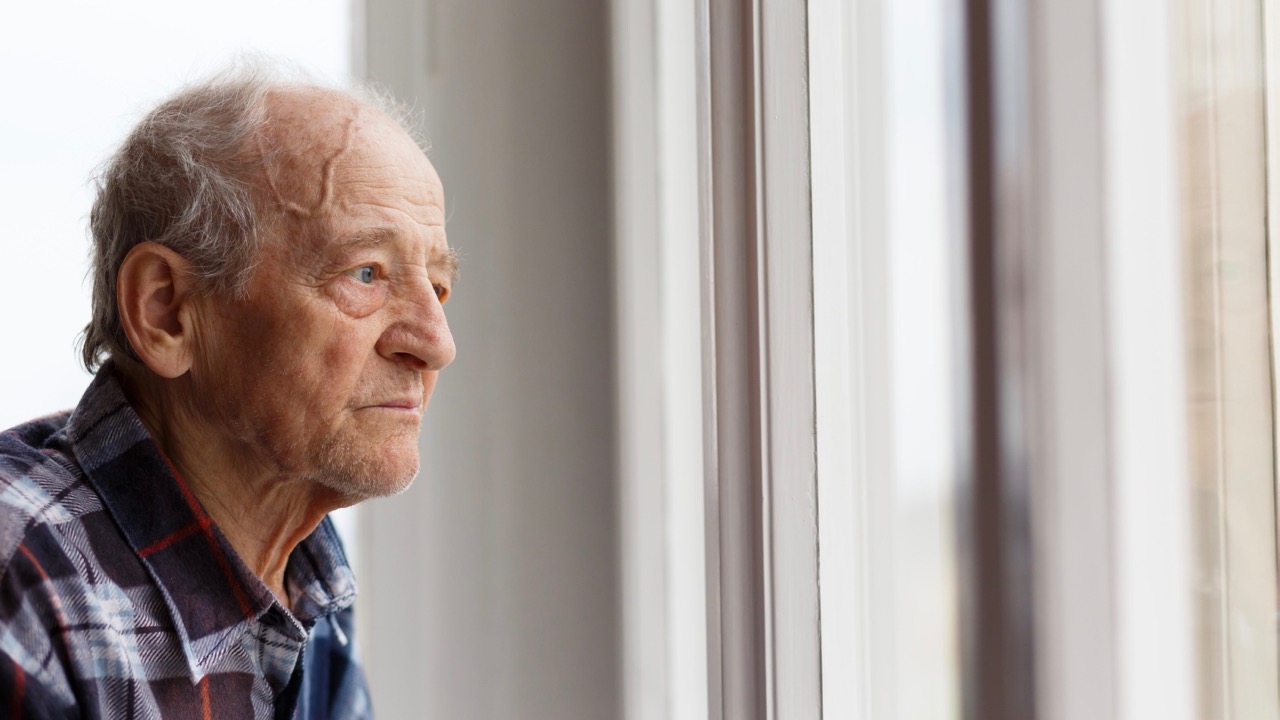 Älterer Mann blickt aus Fenster